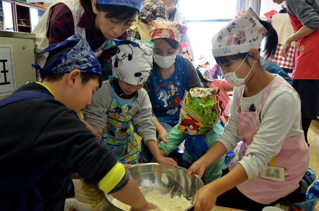 大きなボールで生地を作っている子どもたちの写真