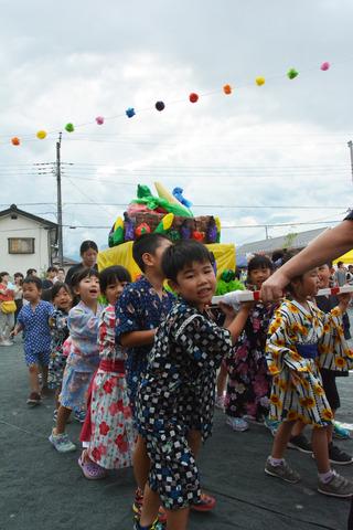 竜王西保育園の園庭にて神輿を担いでいる園児たちの写真