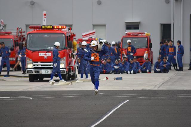 (写真)ポンプ車操法にてホースを担いで走る団員