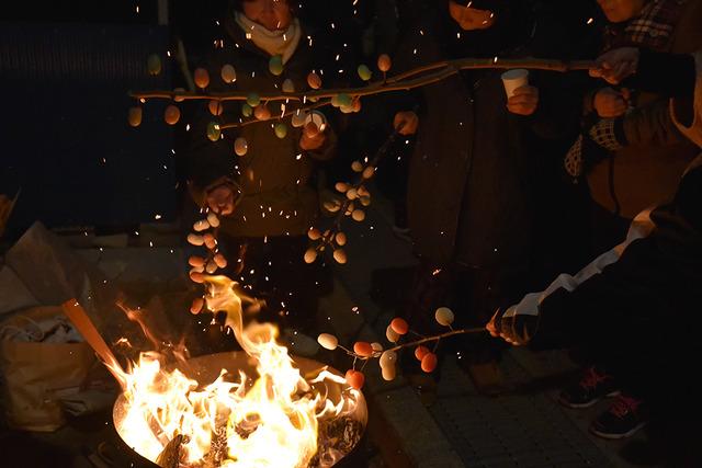 沢山の人が餅花を火に向けている写真