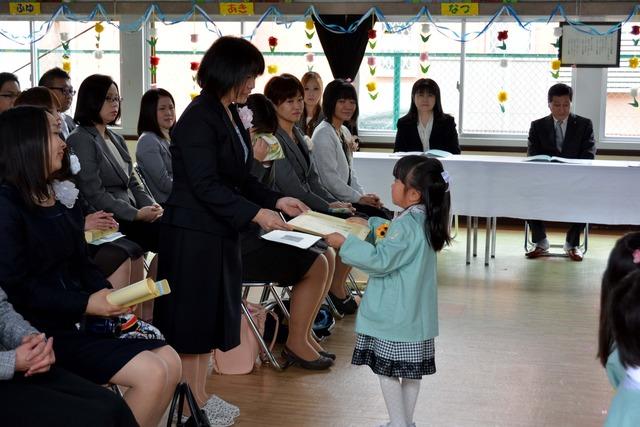 保護者席で待つお母さんへ卒園証書を渡す園児の写真