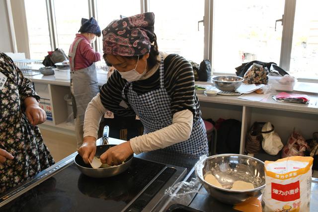 フライパンに生地を乗せている女性の写真