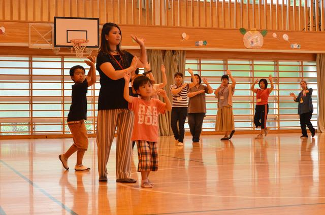 体育館で円を組んで双葉音頭を踊る児童と保護者たちの写真