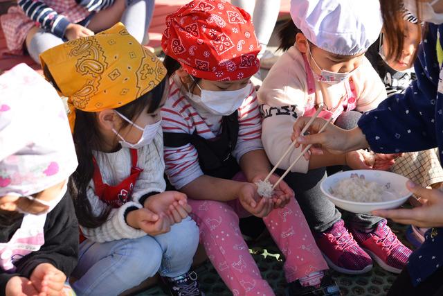 エプロンとマスクを付けて、もち米の試食をしている子供たちの写真