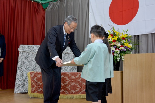 舞台上で幼稚園の銘板と園旗が園児代表から返還される様子の写真