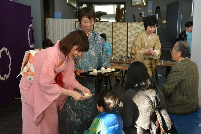 琴を聞いている人にお茶とお菓子が配られている写真