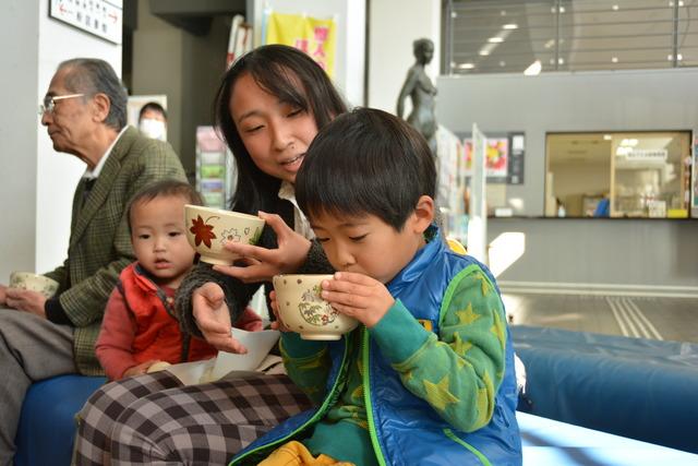 座ってお茶を飲む親子の写真