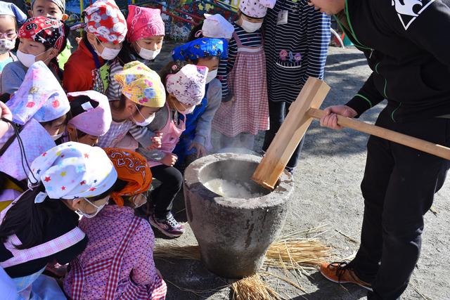 石臼を覗き込むように餅つきを見ている子供たちの写真