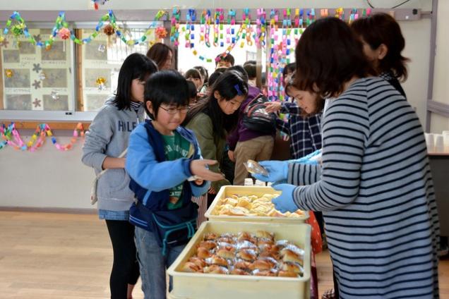 給食の試食コーナーでパンが配られている様子の写真