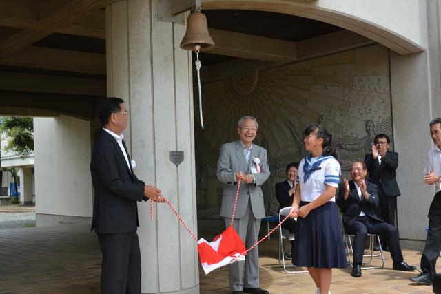 前校長の北川俊明さん、保坂武甲斐市長、生徒会長坂東彩奈さんが紅白の幕を引いている写真
