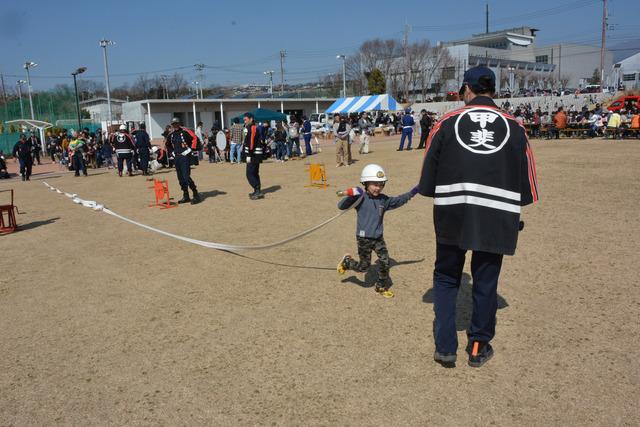 島上条公園にて男の子が消防団の方と一緒にホース投げ体験をしている写真