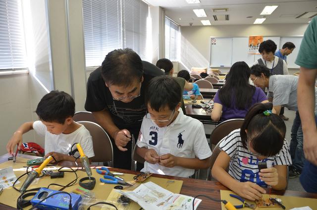 子どもたちが細かい部品を持ち、組み立て作業をしている写真