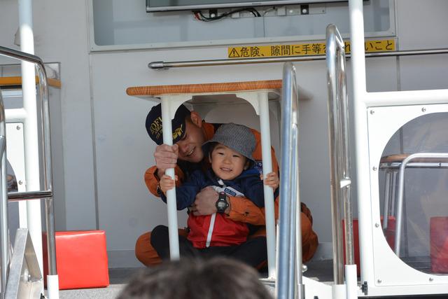 島上条公園にて験甲斐市消防団職員と一緒に男の子が起震車体験をしている写真