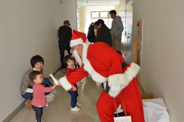 サンタさんからクリスマスプレゼントを受け取っているこどもの写真