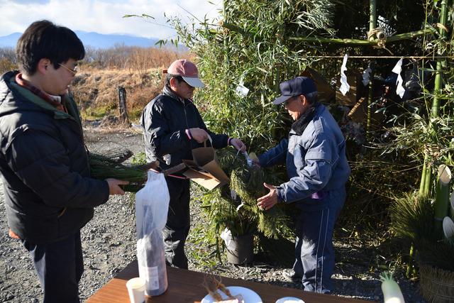 正月飾りを持って集まる区民の写真