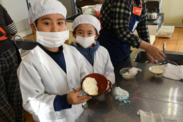 完成した豆腐をお椀に入れ、カメラに向けて持っている児童の写真