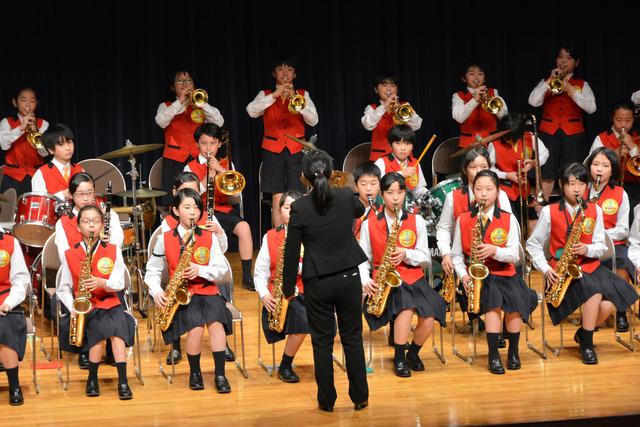 赤いベストを着た小学生たちが楽器を演奏している写真