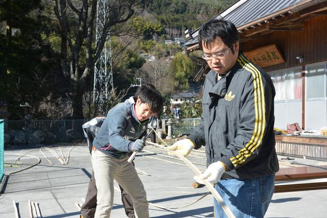 二人で協力して丈を割いている青年会のメンバーの写真