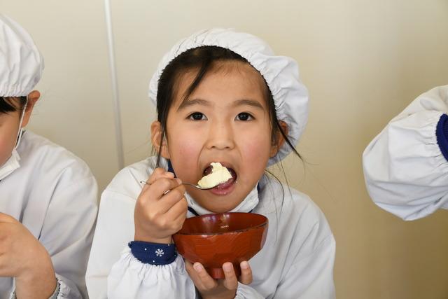 完成した豆腐をスプーンですくって食べている児童の写真