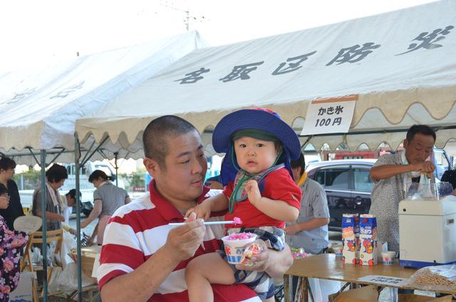 男性が赤ちゃんを抱き、かき氷を食べさせている写真
