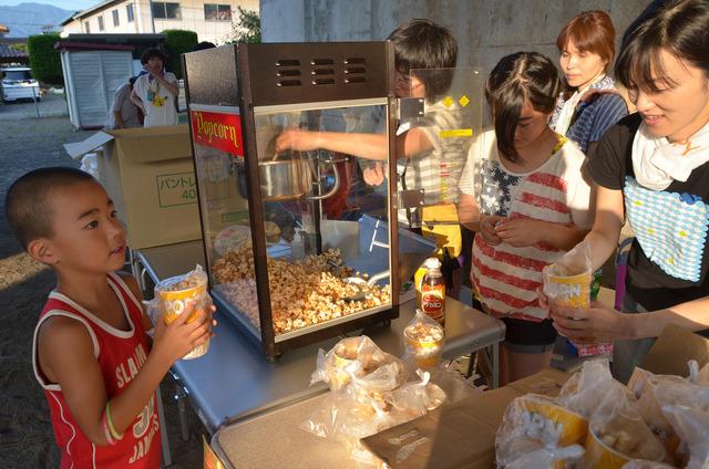 ポップコーンマシン前で小学生くらいの男の子がポップコーンを受け取っている写真