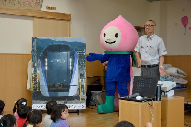 駅員とキャラクターが今後運行が予定されている中央線の特急型新型車両の写真を紹介している写真