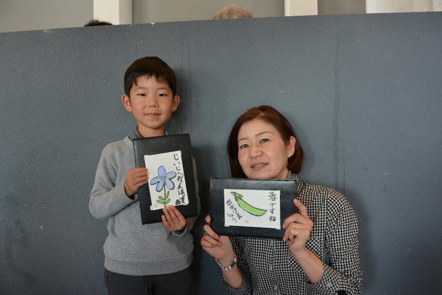 女性と男の子が自分の絵手紙作品を持っている写真