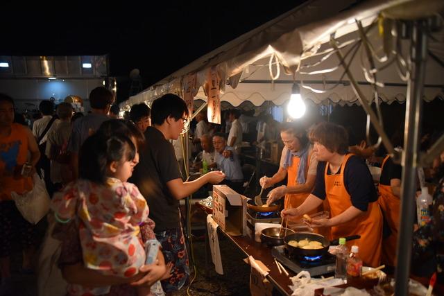 露店のテントが立ち並び、人々が店をみて歩いている写真