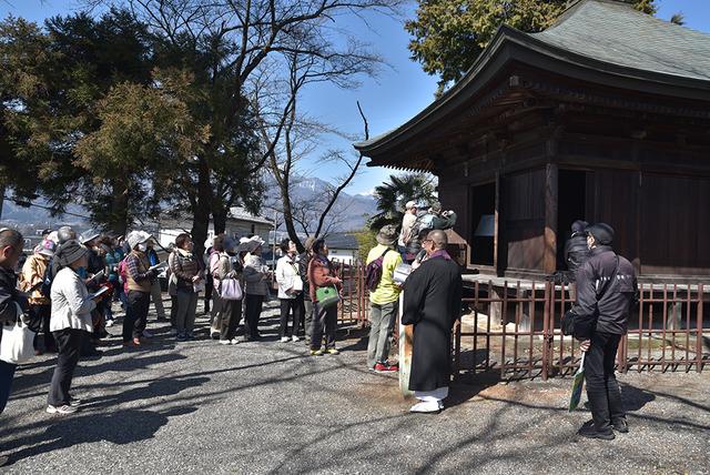 光照寺で住職から薬師堂の由来などの説明を受けている写真