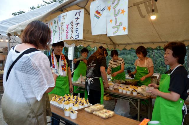 屋台で調理する緑のエプロンをつけた女性たちの写真