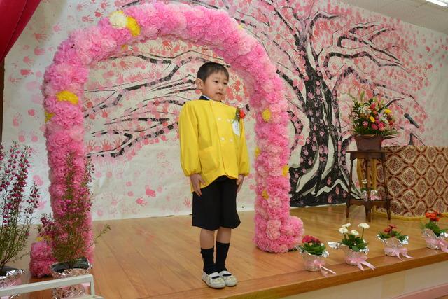 紙で作った花の門に立つ園児の写真