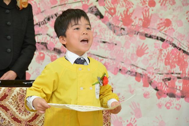 手形で彩られた桜の絵をバックに大きな口をあけて夢を披露する園児の写真