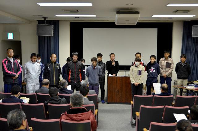 山梨県1周駅伝競走の壮行会で選手達が前に並び、監督がマイクで話している写真