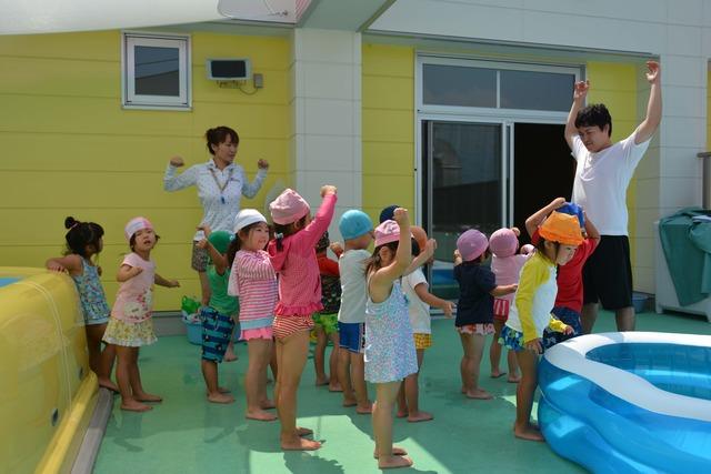 園児たちが水着姿で準備運動をしている写真