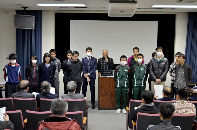 山梨県1周駅伝競走の壮行会で選手達が前に並び、監督がマイクで話している写真