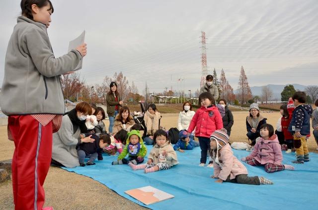 先生が読んでいる紙芝居をたくさんの子どもたちが興味津々に聞いている写真