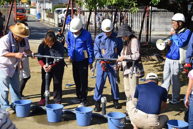 竜王東小学校で参加者の女性2人が貯水槽の操作を体験している写真