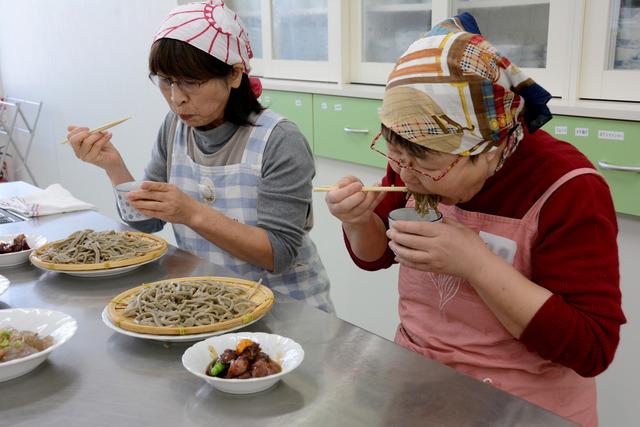2人の女性が出来上がったざる蕎麦を食べている写真