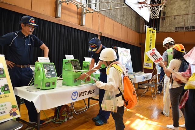 NTT東日本の担当者が参加者の女の子に公衆電話の前で説明をしている写真