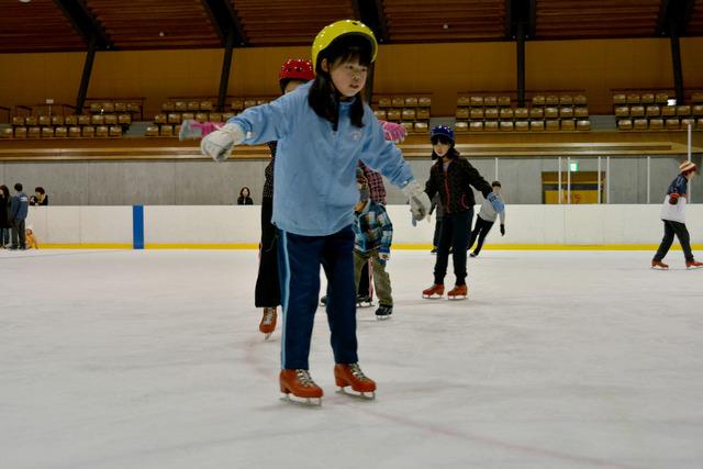 両手を広げバランスを取りながら一人でスケートしている女の子の写真