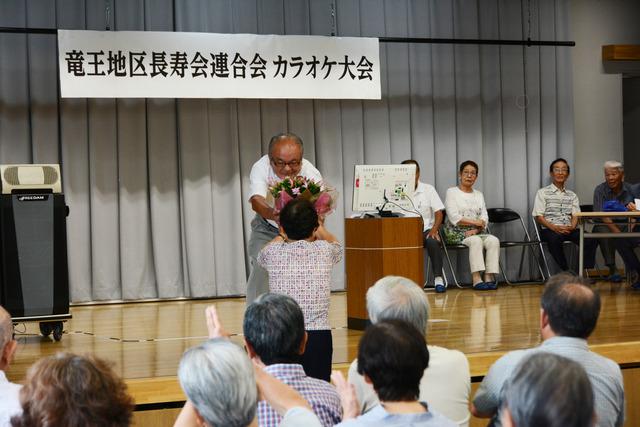 カラオケ大会 人に花を渡している写真
