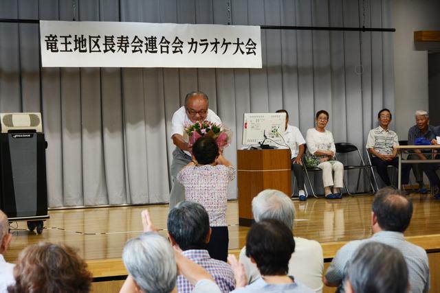 カラオケ大会 人に花を渡している写真