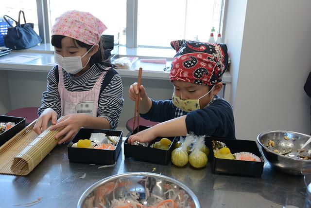 (写真)小さな重箱に料理した品をつめていく