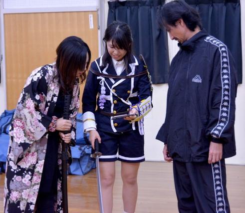 講師の手塚義幸さんと参加者の2人の女性がスマートフォンを見ている写真