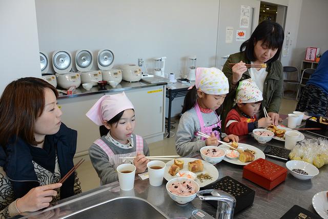 (写真)子ども達が頑張って作った料理を嬉しそうに味見する保護者と子どもたち