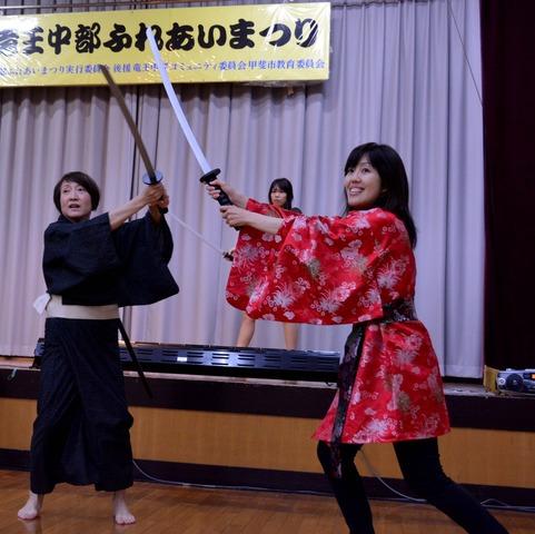 衣装を着た3人の女性参加者が殺陣の練習をしている写真