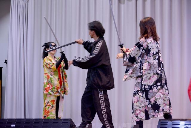 2人の女性参加者が手塚さんと刀を合わせている写真