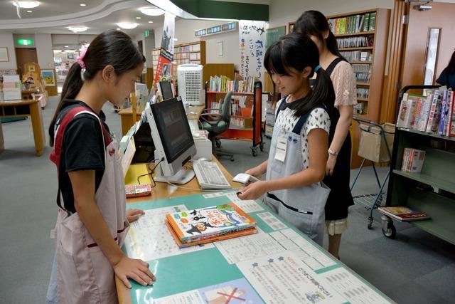 1人の女の子が端末の操作をし、1人の女の子がその様子を見ている写真