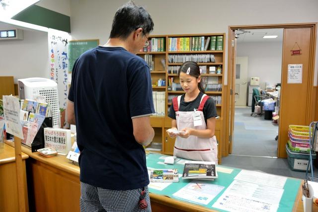 女の子が男性に貸出処理をしている写真