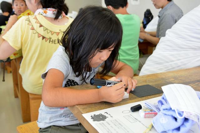 女の子が黒いマジックでデザインの下書きをしている写真